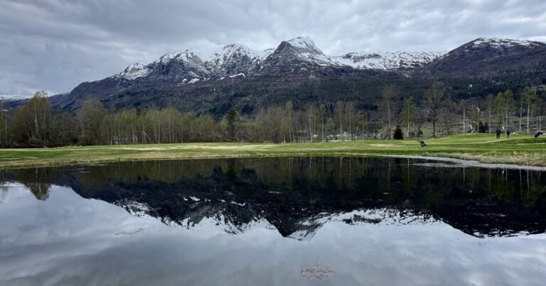 Snow-capped mountains reflected in a still pond near Voss, Norway