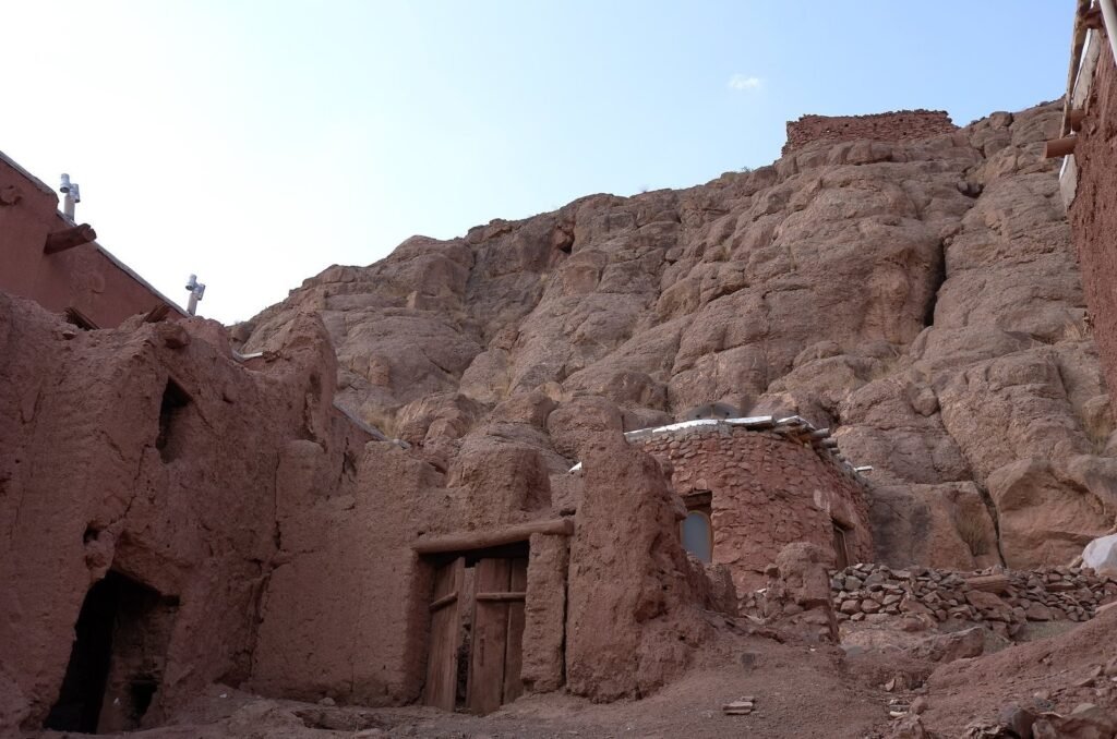 Old red houses below a rock face in Abyaneh