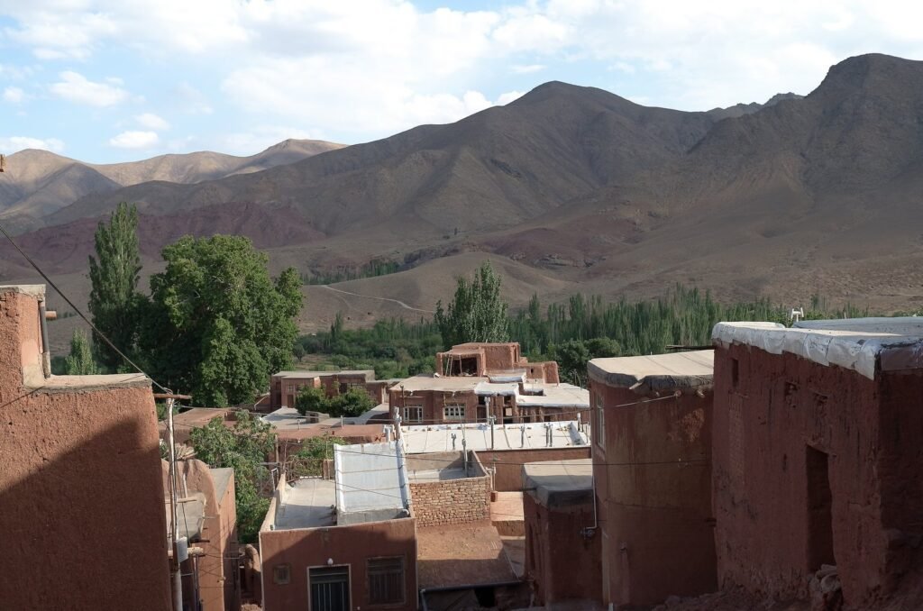 Rooftops of Abyaneh with trees and mountains behind