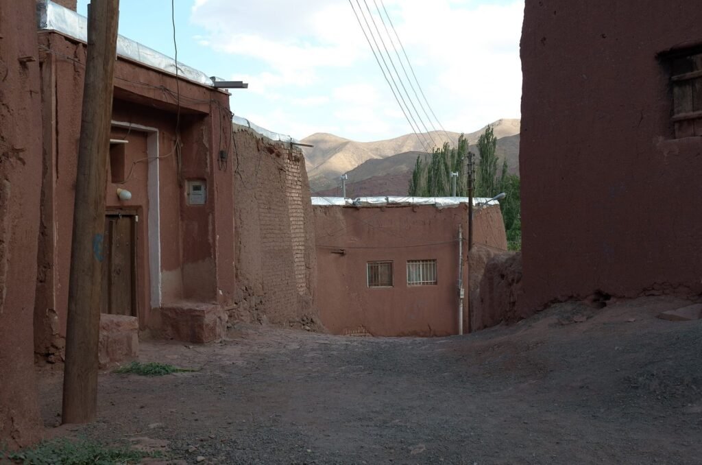 Street with red mud houses and a pole in Abyaneh