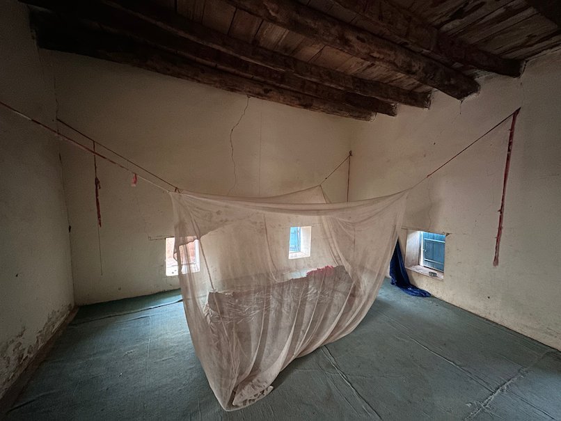 A simple room with a mosquito net over a mattress in a desert guesthouse.