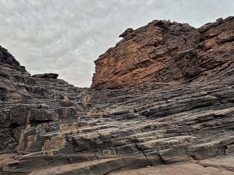Layered sandstone rocks form a narrow gorge under a grey sky.