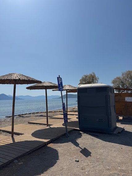 Straw beach umbrellas and a wooden deck by the sea in Aegina