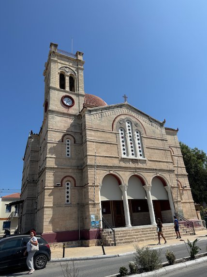 Large church with a clock tower and arches in Aegina