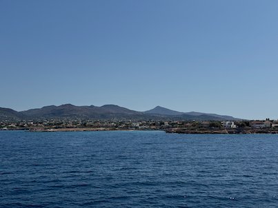 Coastline with small houses and hills across the calm Saronic Gulf