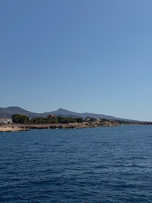 Low coastline and hills of Aegina across deep blue water