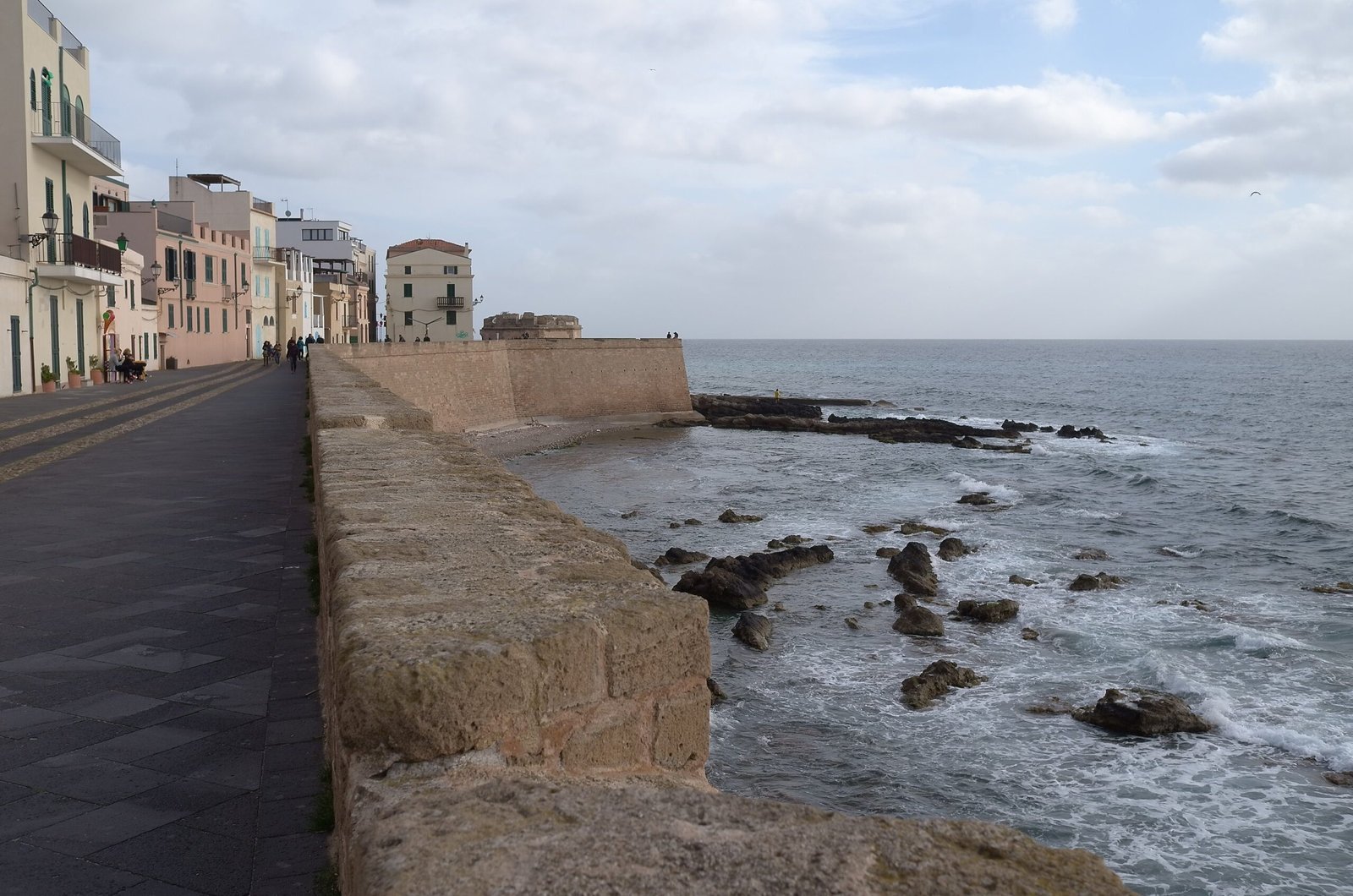 The old ramparts of Alghero rise above dark rocks and the sea.