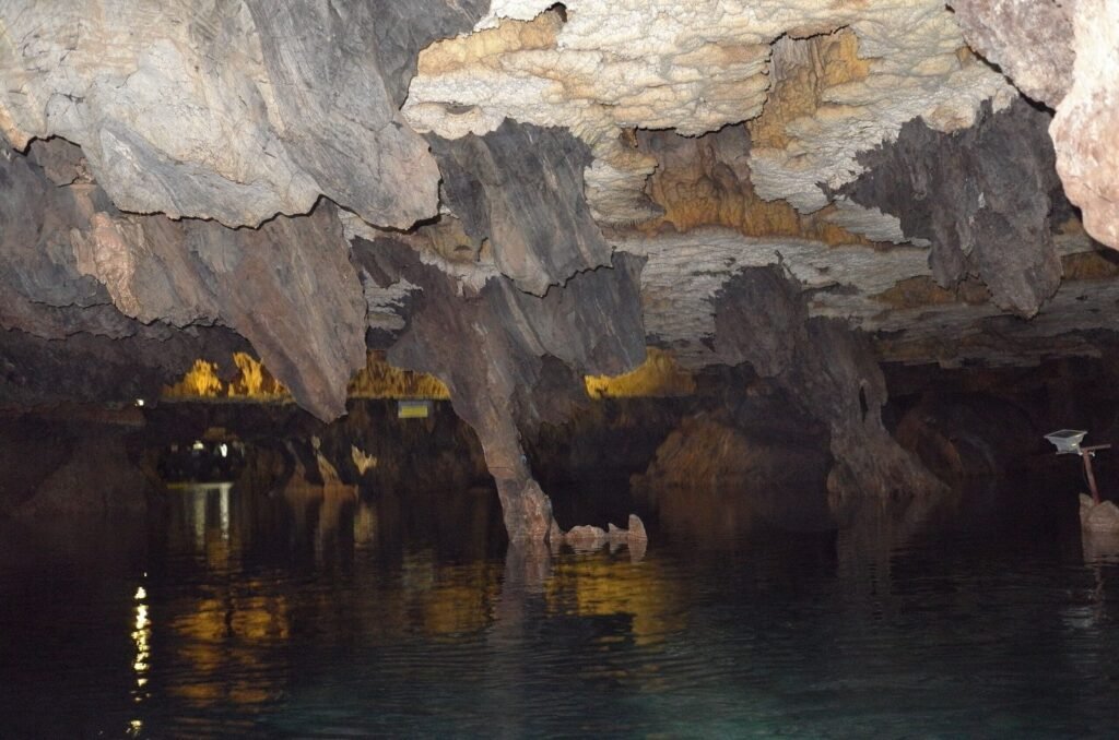 Cave lake with boat lights and rock pillars in Ali Sadr Cave