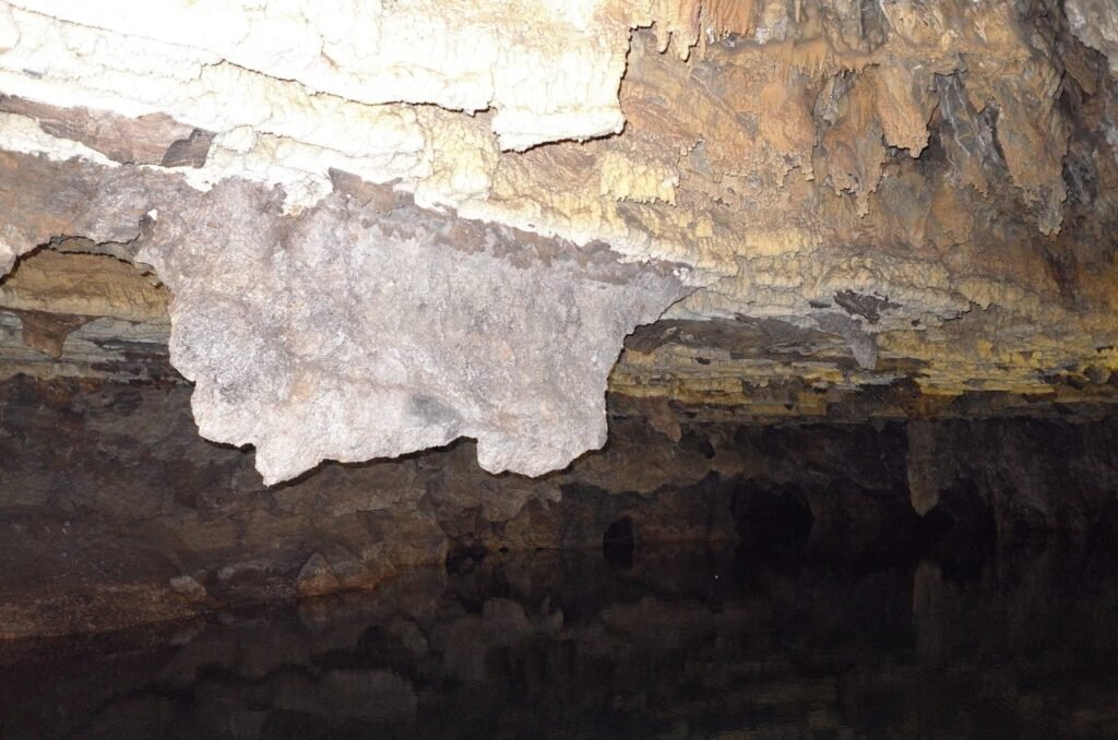 White rock that hangs above dark water in Ali Sadr Cave