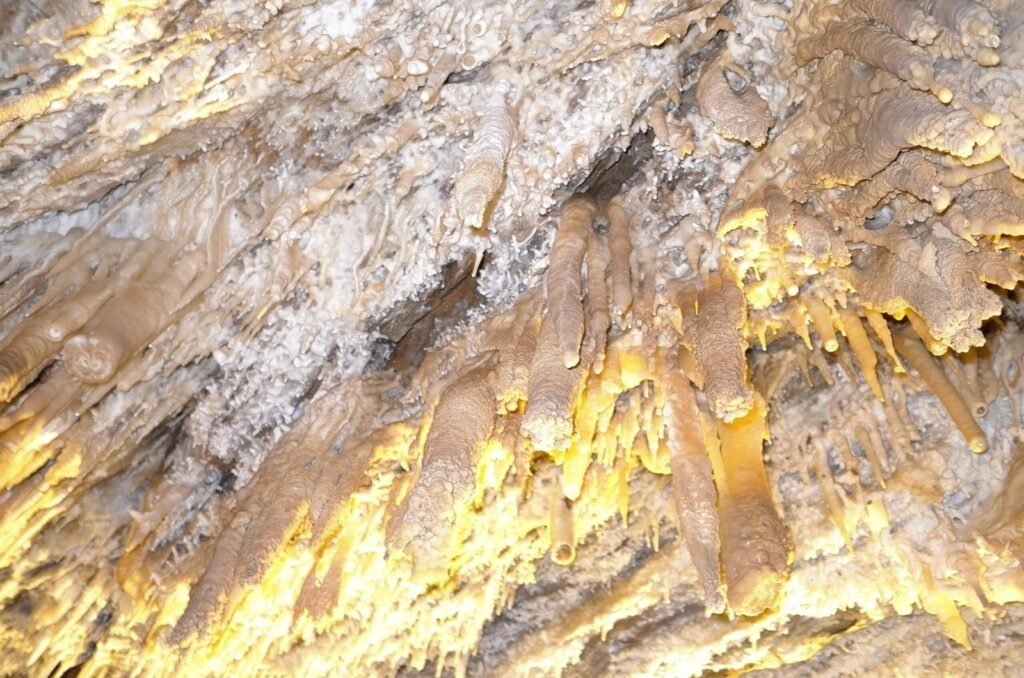Yellow lit stalactites on the cave ceiling of Ali Sadr Cave