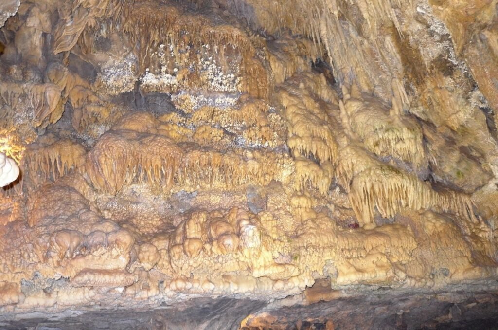 Brown rock layers with thin stalactites in Ali Sadr Cave