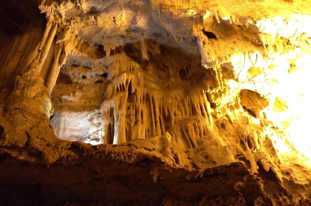 Yellow lit stalactites and rock curtains in Ali Sadr Cave