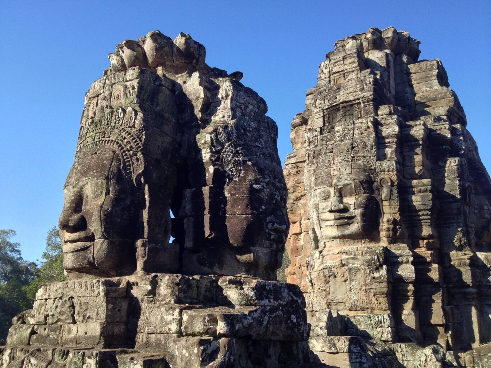 Large carved stone faces look out from the towers of the Bayon temple at Angkor.