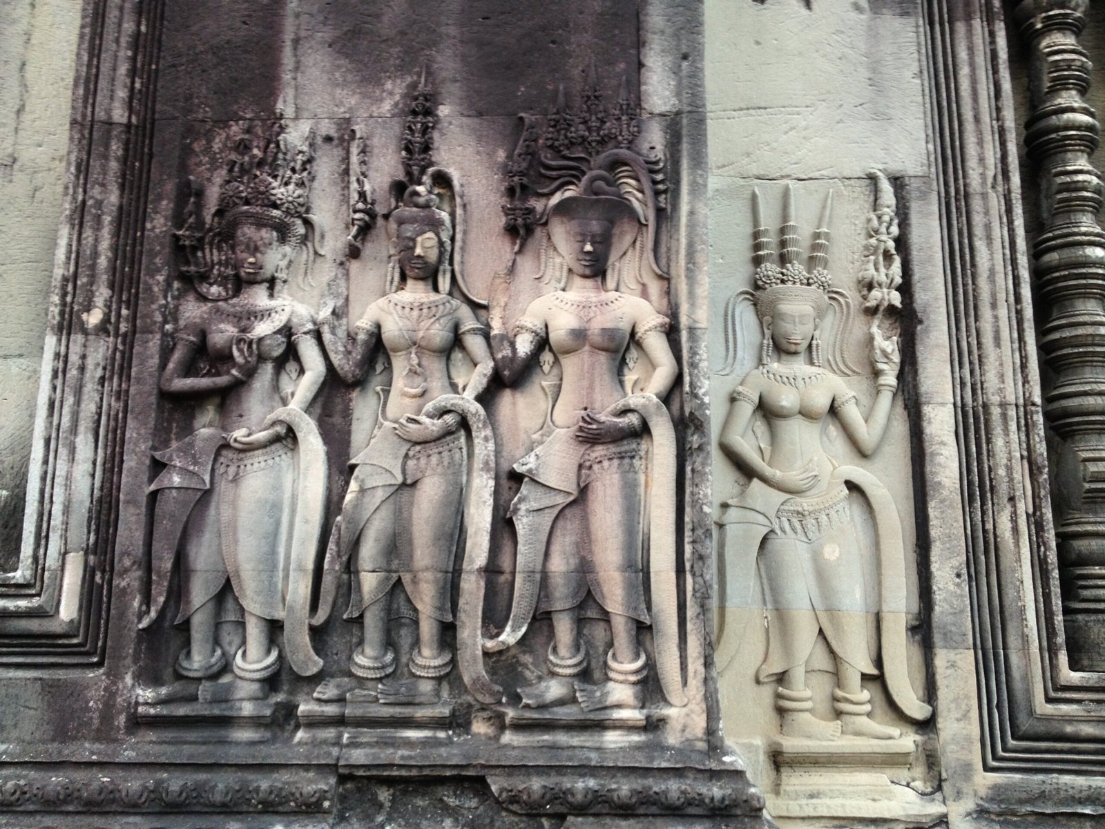 Carved apsara dancers decorate a stone wall at Angkor Wat in Cambodia.