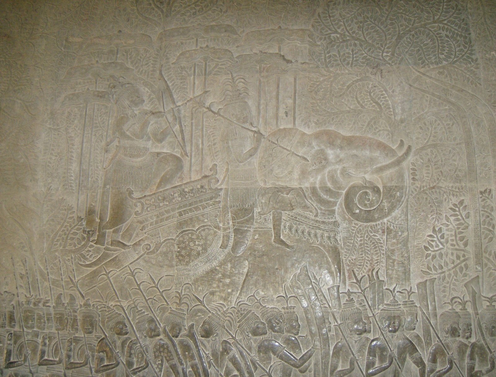 A detailed stone bas-relief shows a battle scene at Angkor Wat near Siem Reap.