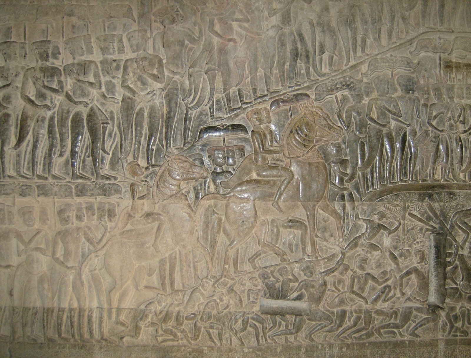 A long bas-relief with many carved figures covers a gallery wall at Angkor Wat.