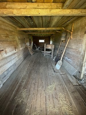 Inside an old wooden barn at Askhult, with a wooden floor and old farm tools