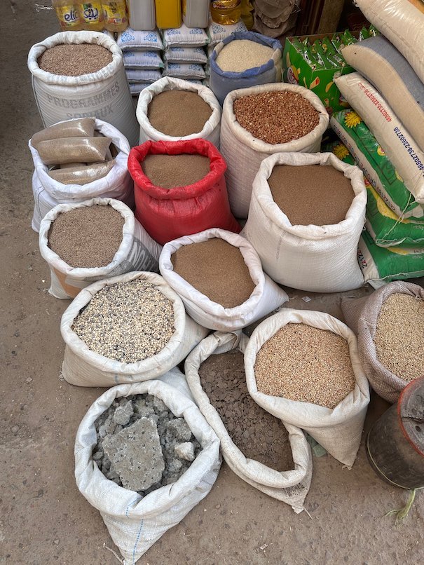 Open sacks of grain and flour stand together at a market.