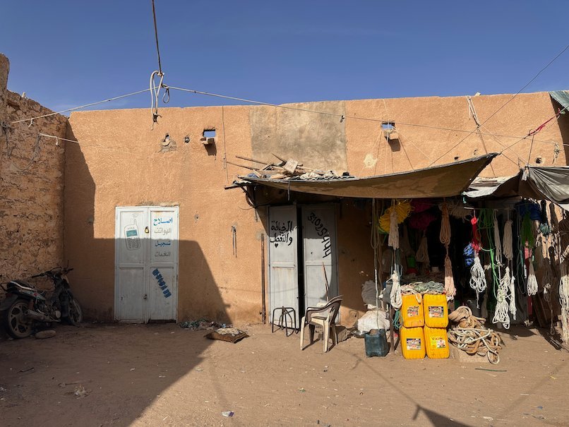 A small shop with goods outside stands on a sandy street in Atar.