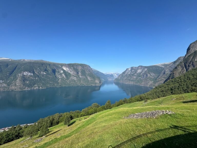 The Aurlandsfjord far below green slopes and steep mountains, seen from the Aurlandsfjellet road