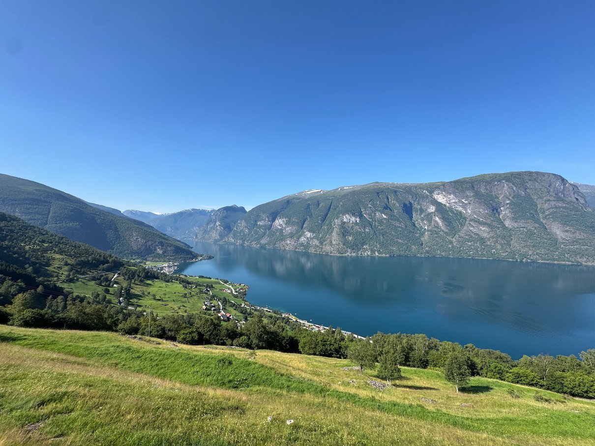 Wide view of the blue Aurlandsfjord between steep mountains on a clear summer day