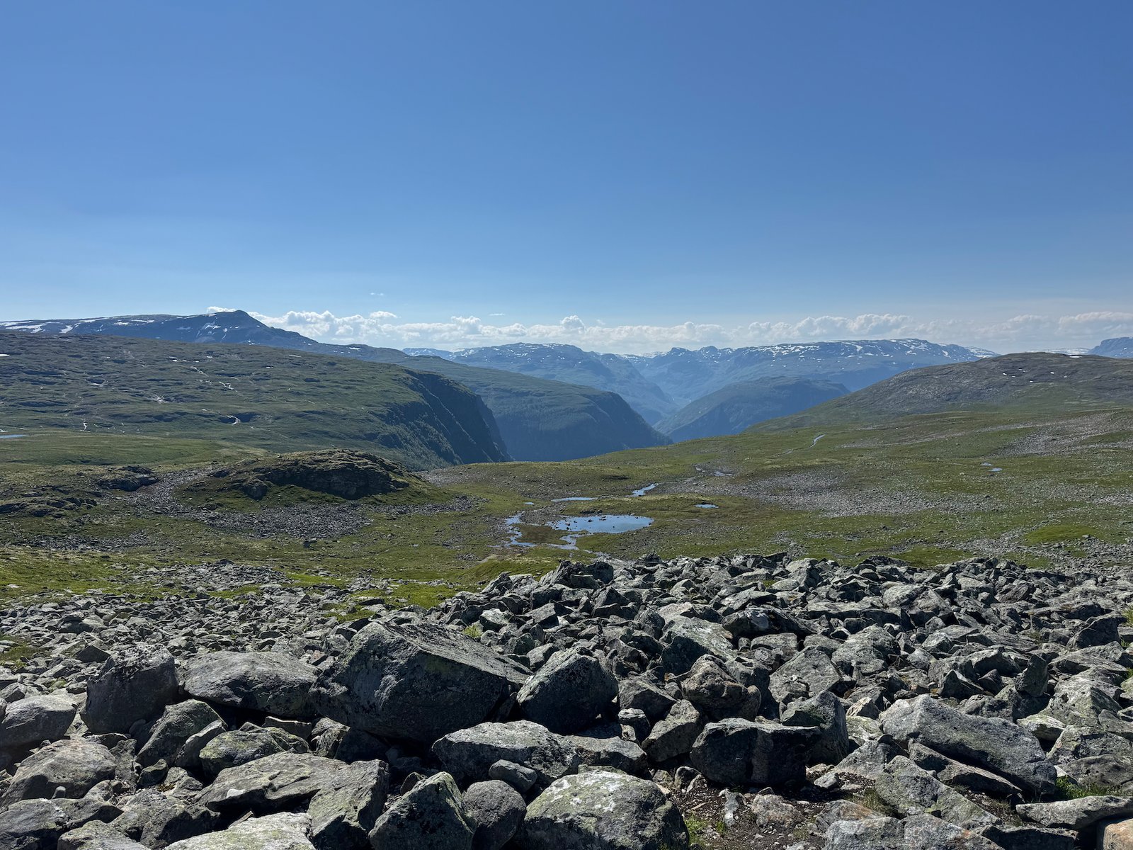 Field of large boulders on the mountain, with a deep valley and peaks behind