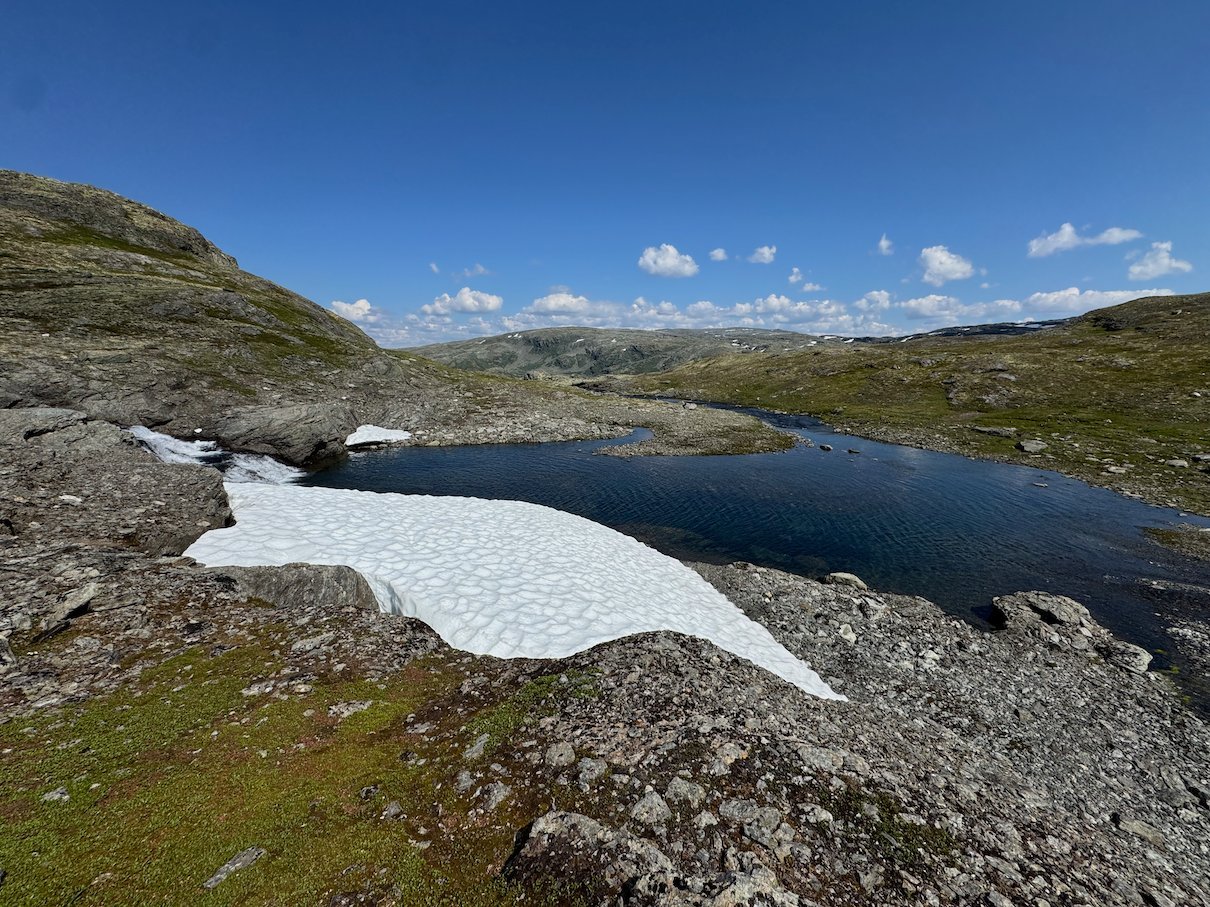 Dark mountain lake and a white snow patch on Aurlandsfjellet