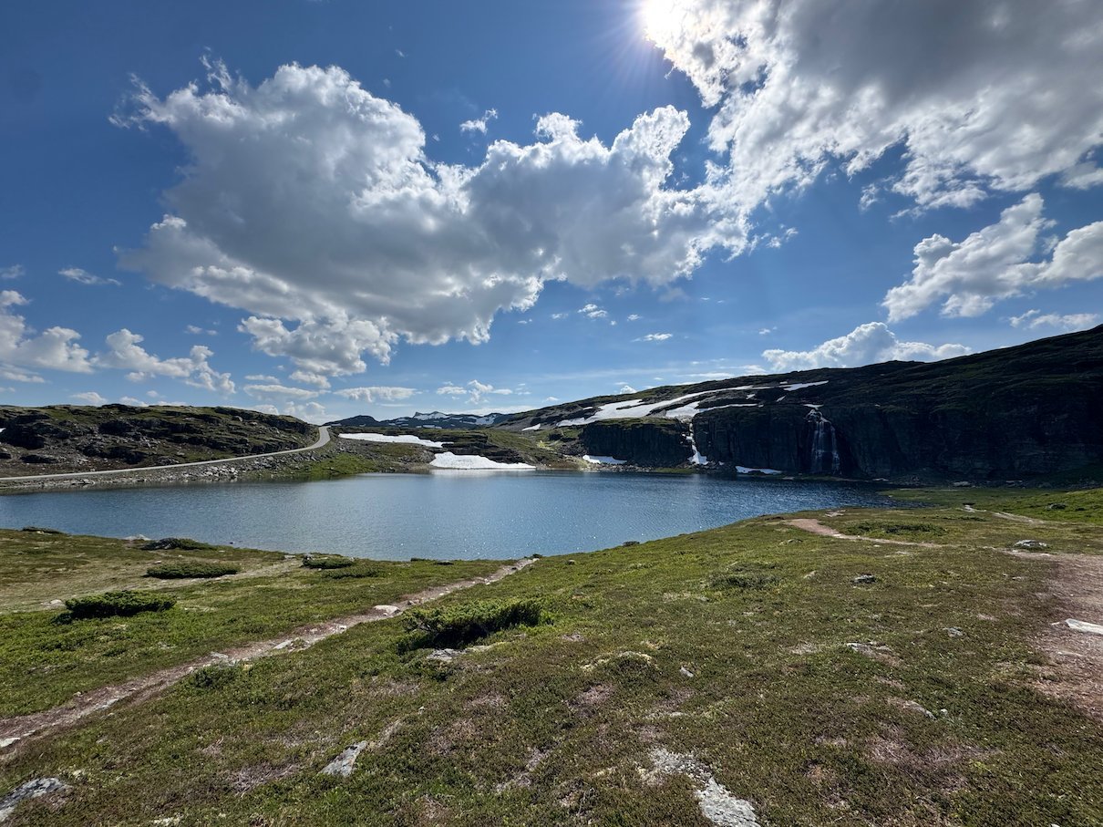 The scenic road beside a mountain lake, with snow on the hills