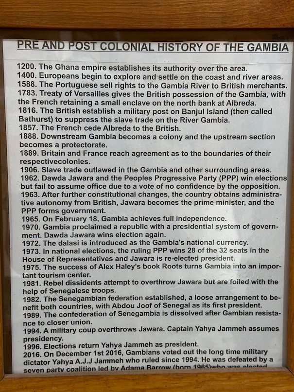 A framed panel lists the history of The Gambia in the museum at Kachikally, Bakau.