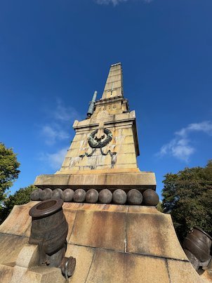 Battle of Lund obelisk seen from below, with old cannons and cannonballs at the base