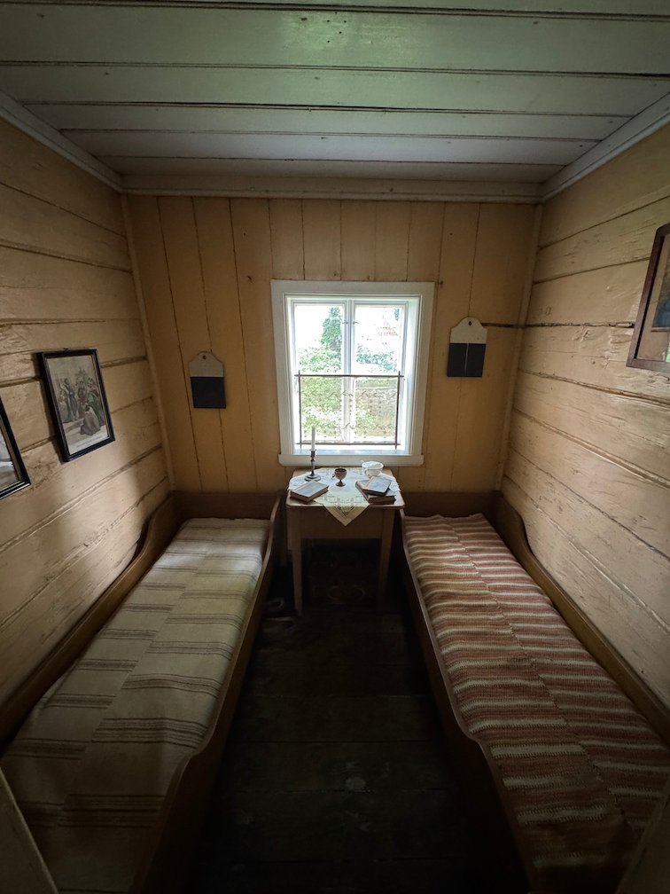 Small patient room with two narrow wooden beds and one window at the Leprosy Museum in Bergen