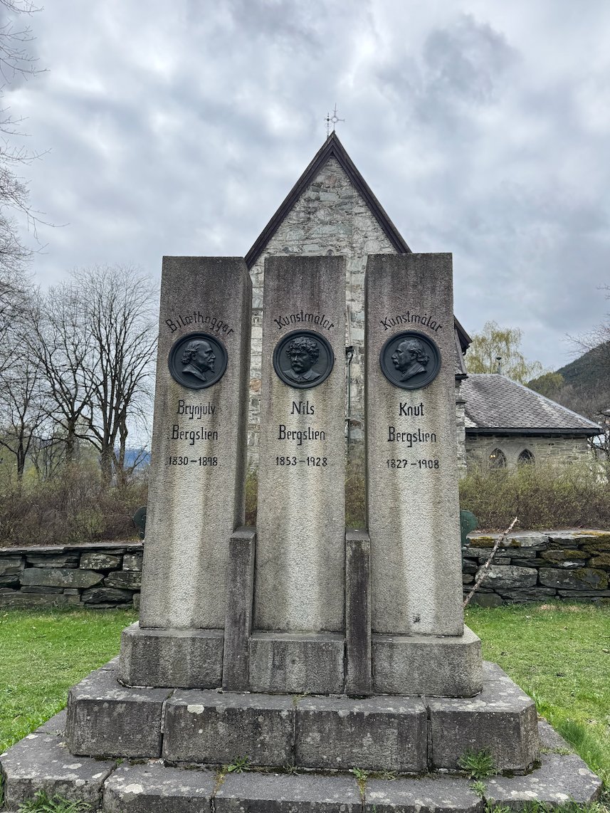 Stone memorial with three bronze portrait medallions of the Bergslien family in Voss