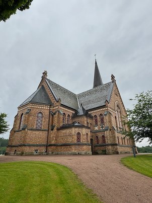 Side view of a large brick church with a gravel path in Borås