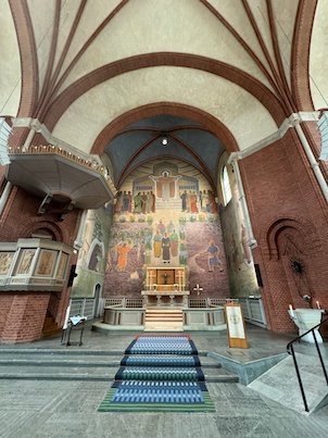 Church interior in Borås with a large painted altar wall and brick arches