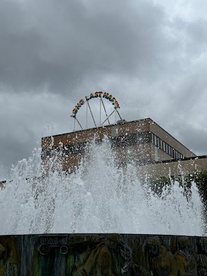 Close view of fountain spray in front of a building with a rooftop sign