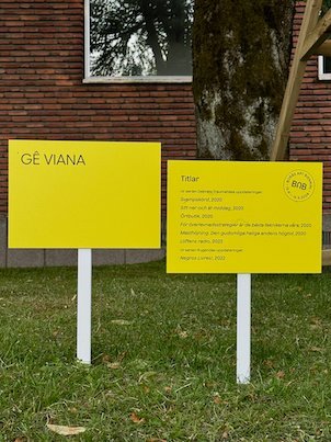 Yellow signs Gê Viana with information about the artworks