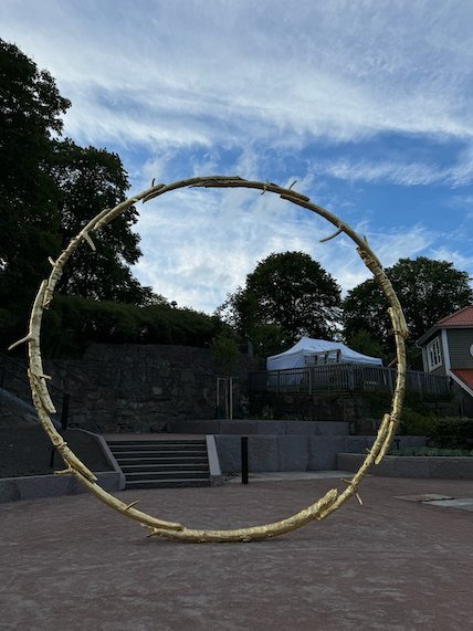 Large golden ring sculpture on a paved square in Borås