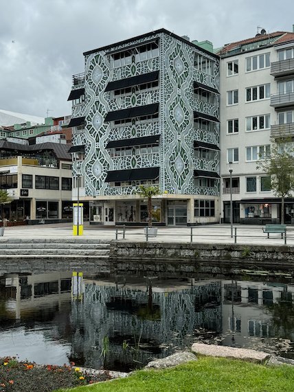 Building with a lace pattern facade, reflected in the river