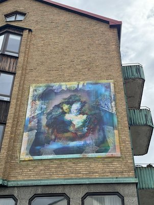 Mural of a woman in soft colours on a yellow brick wall in Borås