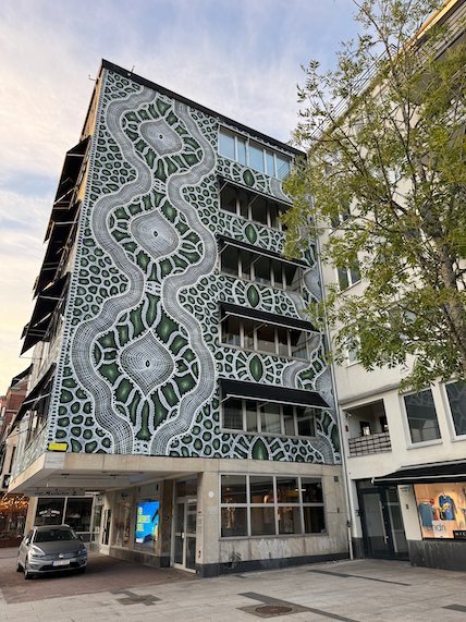 Tall building with a green and white patterned facade in central Borås