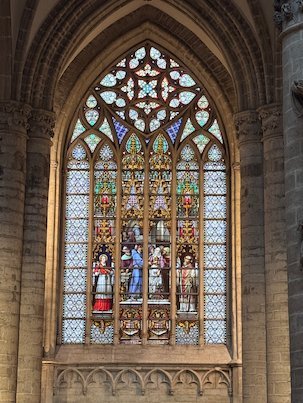 A colorful Gothic window with figures fills an arch in the cathedral in Brussels.