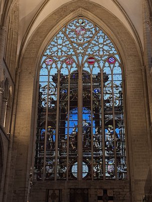 A Gothic stained glass window with blue glass lights the cathedral in Brussels.