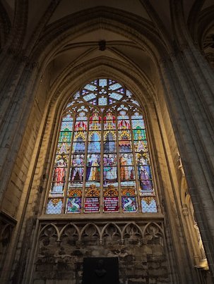 A stained glass window with saints lights a side wall of the cathedral in Brussels.