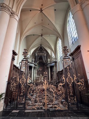 An ornate iron gate stands in front of the choir in a church in Brussels.
