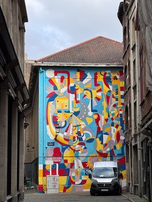 A colorful abstract mural covers the end wall of a building in Brussels.