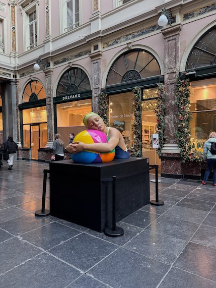 A colorful sculpture stands on a black base in the Galeries Royales Saint-Hubert.