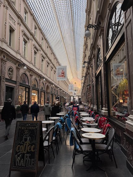 Cafe tables line the glass-roofed Galeries Royales Saint-Hubert in Brussels.