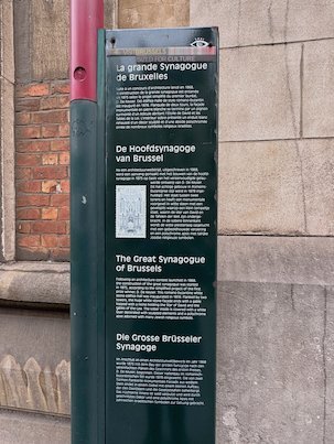 An information sign about the Great Synagogue stands next to its wall in Brussels.