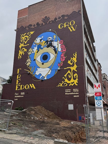 A large mural with an eye and the words Grow Freedom covers a building in Brussels.