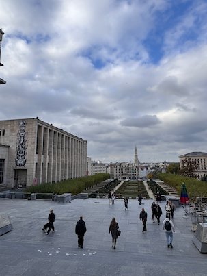 People walk on the Mont des Arts with the Town Hall spire in the distance in Brussels.